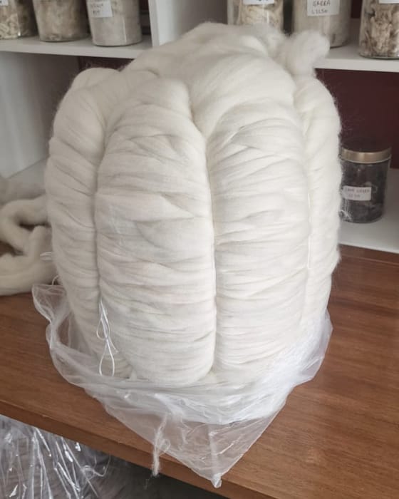 Ein fertiger Kammzugwickel neben Fasermustern im Musterraum der Kämmerei
